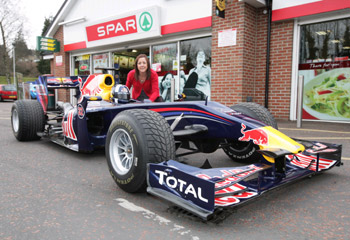 Siobhan McCarney, marketing manager with the Henderson Group with the Red Bull Racing F1 Car and driver at the Spar on Moss Road in Lambeg