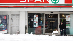 A man clears snow off the pathway outside Spar in Glasnevin, Dublin, after blizzard conditions the previous night