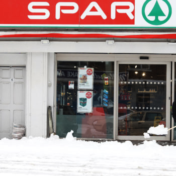 A man clears snow off the pathway outside Spar in Glasnevin, Dublin, after blizzard conditions the previous night
